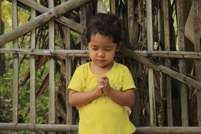 Seorang Gadis Kecil dengan Sebuah Rosario di Tangan di Sebuah Kapel