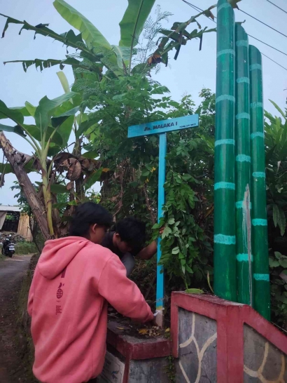 Mahasiswa Kelompok 16 P2MB UPI Sumedang Memasang Plang Nama Jalan di Desa Malaka